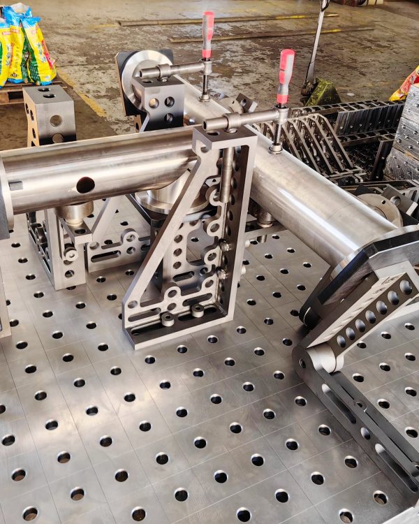 DCT 3D welding table with modular fixtures for pipe welding. Precision V-blocks and clamps hold round tubes securely, ensuring accurate alignment and stable welding. Ideal for pipe fabrication, the nitrided surface resists spatter and wear, making it perfect for high-efficiency, professional welding environments.